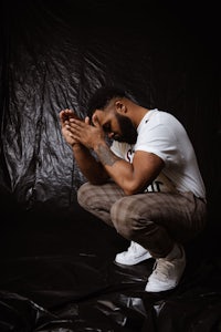 a man kneeling down with his hands on his knees